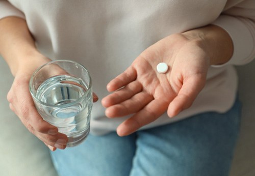 A patient holding a pill and a glass of water